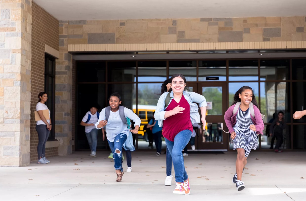 Students running from school with smiles on their faces.