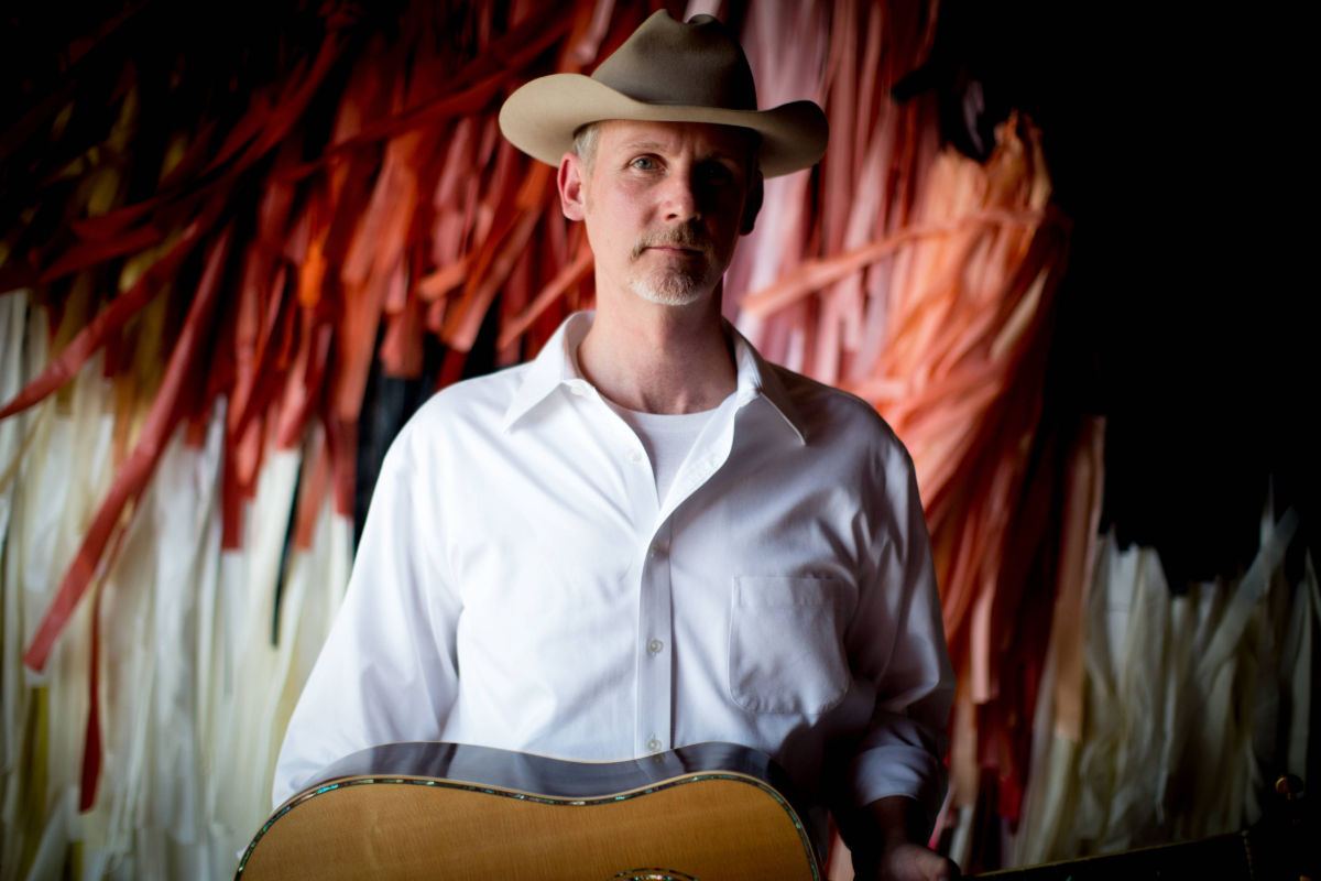 Man holding guitar in front of streamers